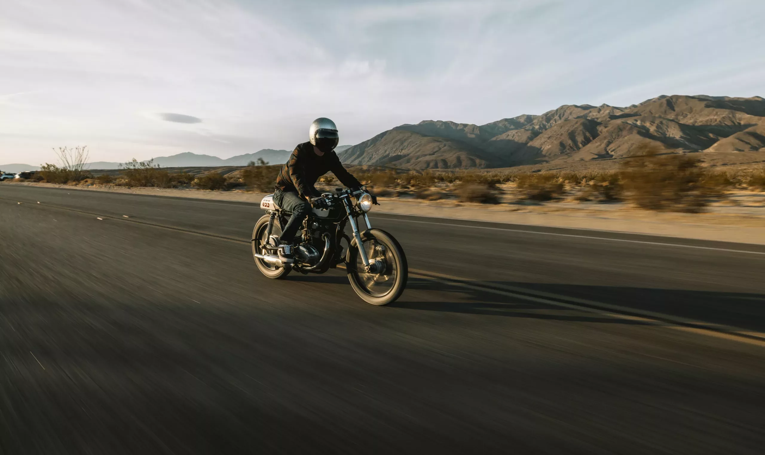 Man riding a motorcycle on a desert road.